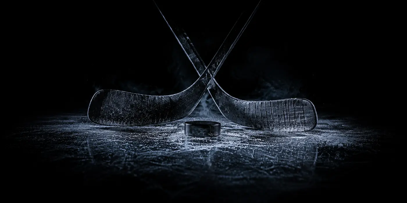 Crossed hockey sticks and a puck on the ice