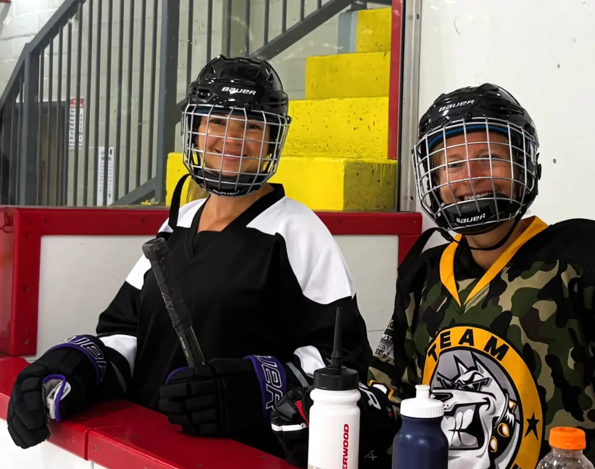 Never 2 Late Hockey participants smiling together on the bench
