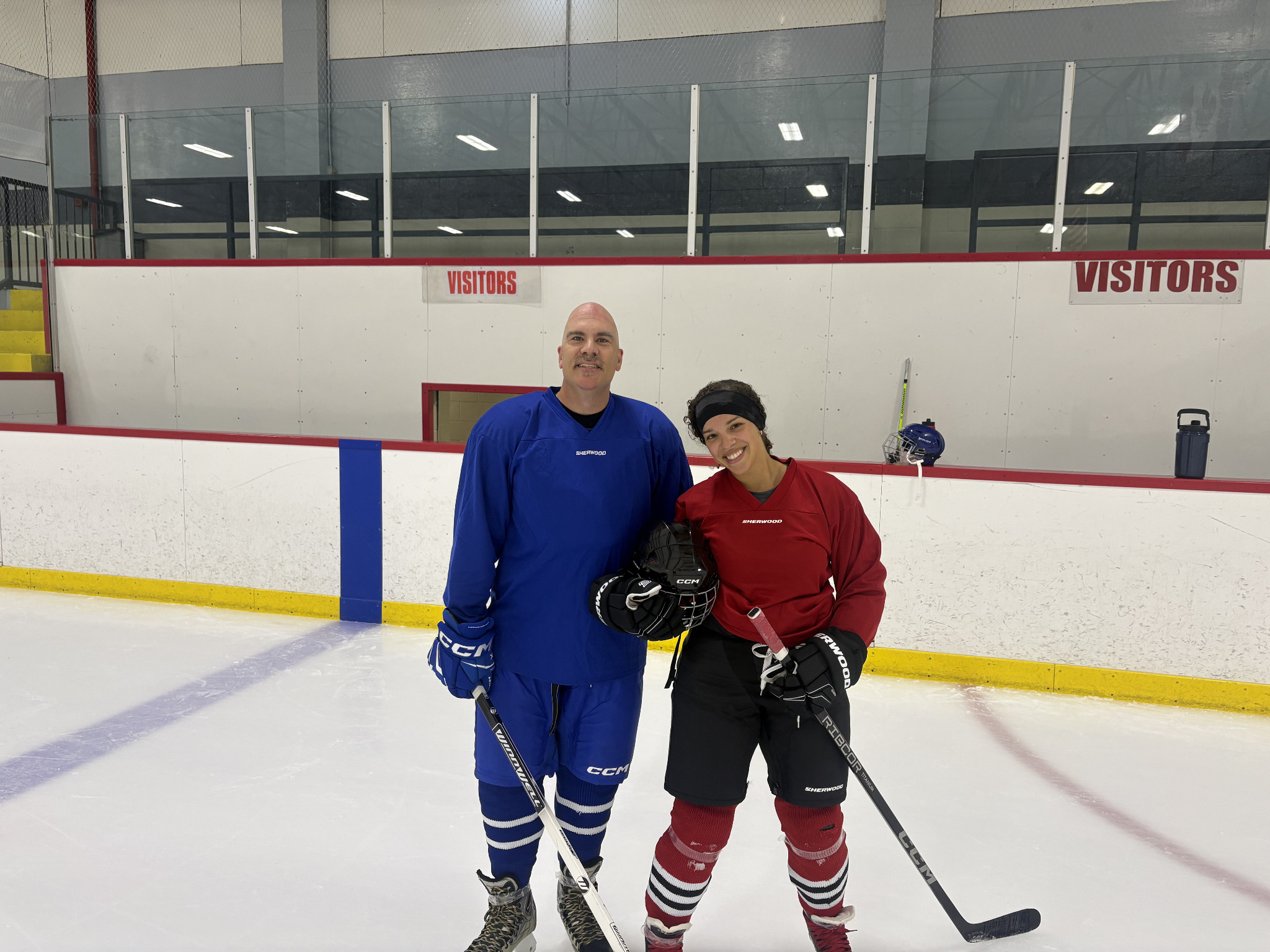 Two Never 2 Late Hockey players smiling on the ice